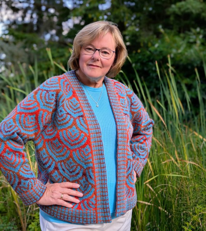 Eine Frau trägt eine Strickjacke in bunten Farben.