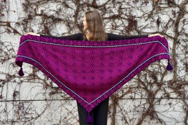 Eine Frau steht mit dem Rücken zur Kamera und zeigt ein ausgebreitetes Tuch.