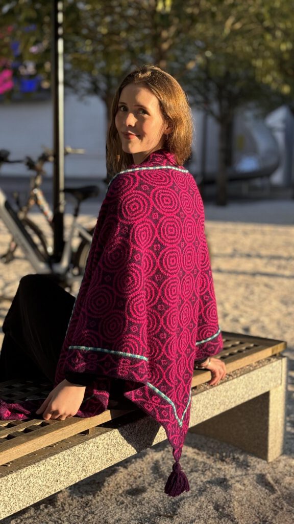 Eine Frau sitzt auf einer Bank und trägt ein schönes Tuch