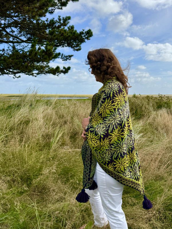 Eine Frau trägt ein Tuch und steht am Meer.